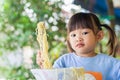 PortraitÃ¢â¬â¹ imageÃ¢â¬â¹ ofÃ¢â¬â¹ 2-3 yearsÃ¢â¬â¹ oldÃ¢â¬â¹ ofÃ¢â¬â¹ baby.Ã¢â¬â¹ HappyÃ¢â¬â¹ AsianÃ¢â¬â¹ childÃ¢â¬â¹ girlÃ¢â¬â¹ enjoyÃ¢â¬â¹ eatingÃ¢â¬â¹ someÃ¢â¬â¹ Royalty Free Stock Photo